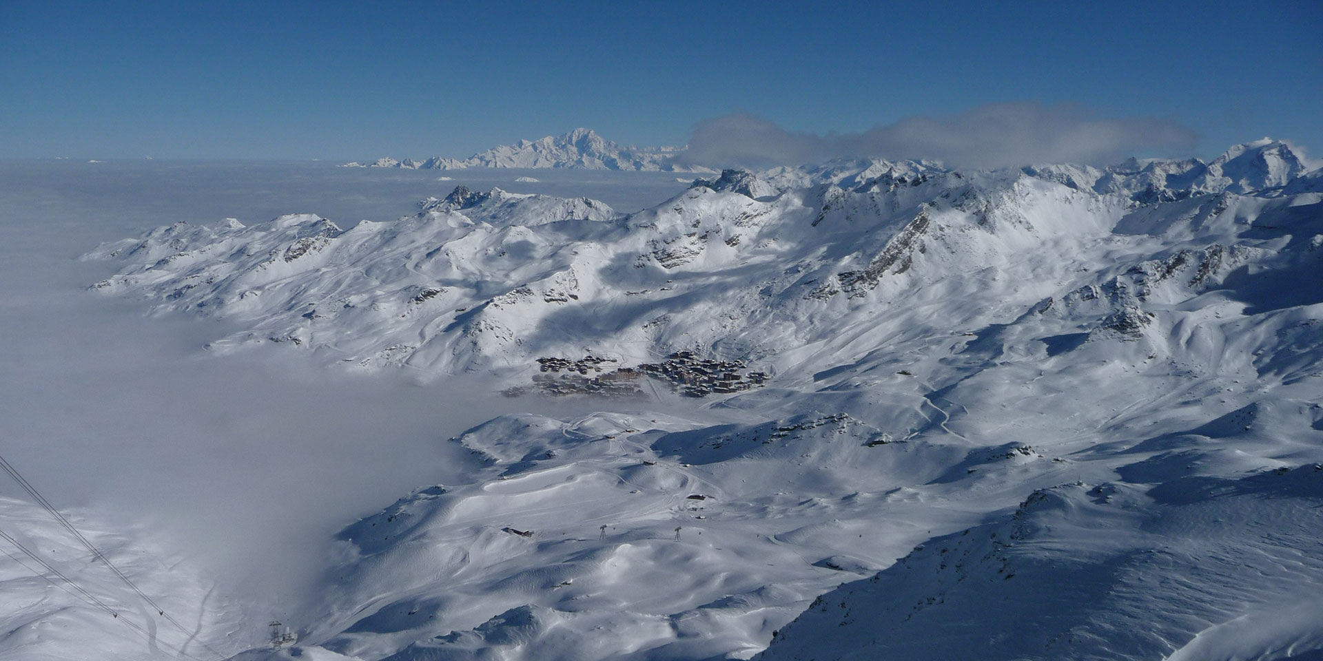 Val Thorens in winter seen from the top of the Cime Caron cable car with Mont Blanc on the horizon.