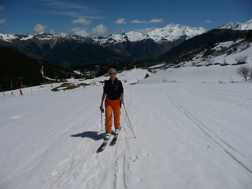 Skieuse en peaux de phoque à la montée sur la piste du Renard à Courchevel. Ambiance printanière.